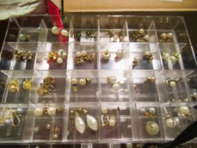 Large quantity of mainly cultured pearl gold mounted stud earrings, housed in a perspex display case