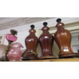 Three matching pottery brown glazed floral decorated lamp bases and an oil lamp with glass well