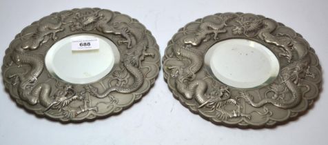 Pair of Oriental circular silver plated table mirrors, embossed with dragons, 21cm diameter Both are