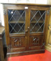 Small reproduction oak bookcase with two leaded and carved panel doors, 72cm wide