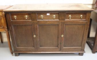 Oak dresser base, the moulded top above three short drawers with brass drop handles, with two