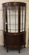 Early 20th Century figured walnut demi-lune display cabinet, the moulded cornice above a bar