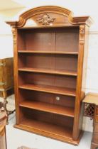 Large mahogany open bookcase, the moulded broken arch cornice above a decorative frieze and