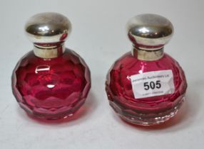 Pair of silver mounted cranberry glass perfume bottles with facet cut bodies, 10cm high each