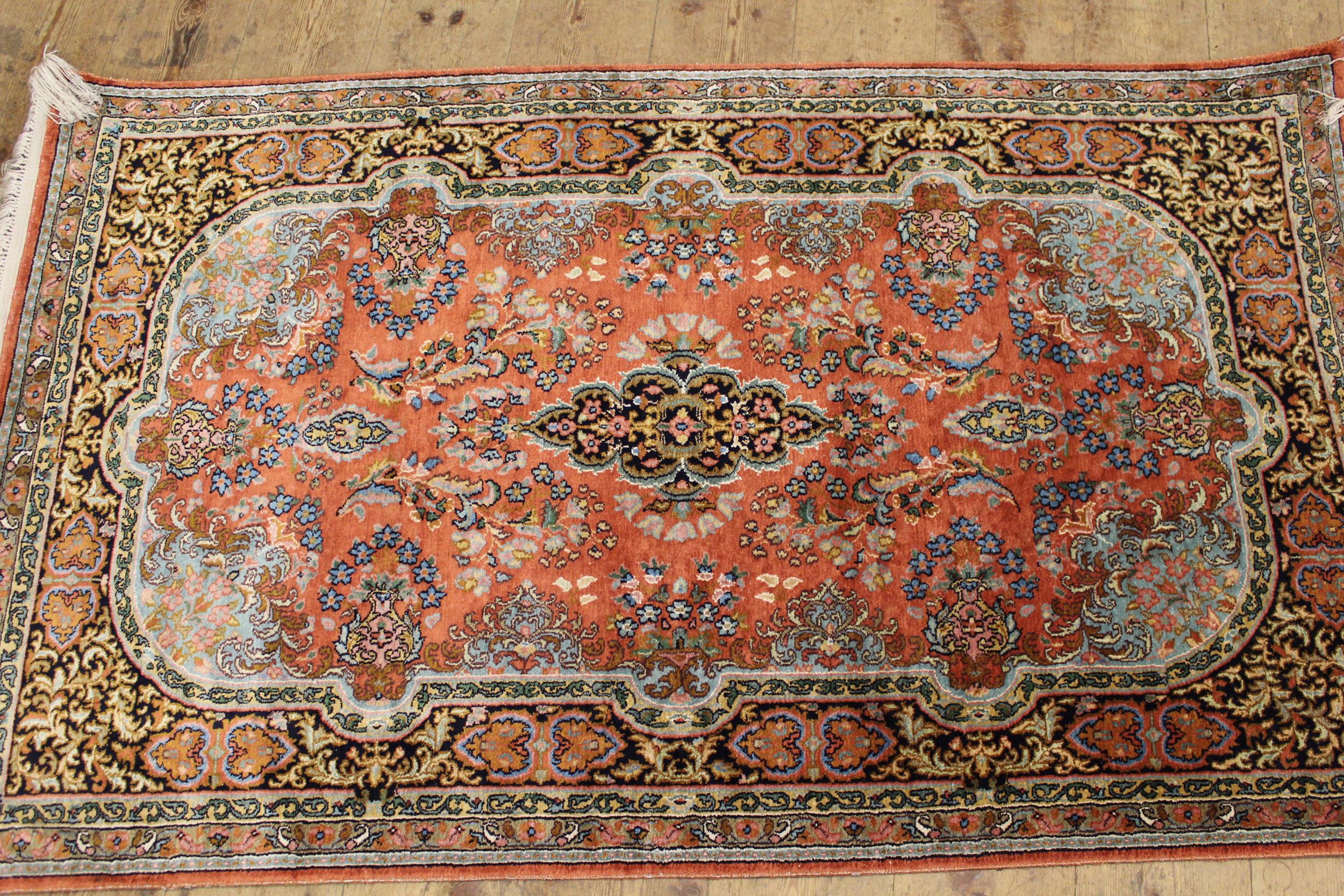 Indian rug with a medallion and all-over floral design on a rose ground with borders, together