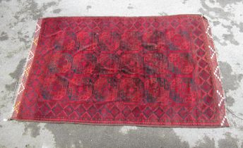 Afghan carpet in shades of deep red and blue (moth damage)