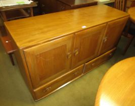 Ercol light ash sideboard, having three panelled doors with two drawers, on casters, 76cm high x