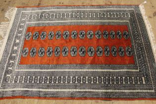 Pakistan Bokhara rug with typical repeating gol design on a terracotta ground, 180 x 130cm, together