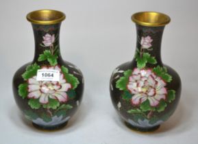 Pair of cloisonne baluster form floral decorated vases on a black ground, 21cm high