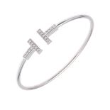 A DIAMOND AND 18CT WHITE GOLD 'T' BANGLE BY TIFFANY & CO.