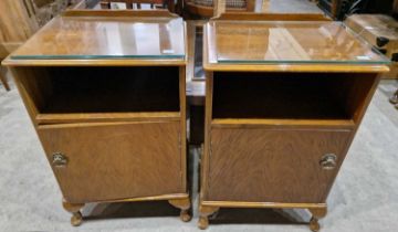 A pair of walnut bedside cabinets with open recesses above cupboard doors.