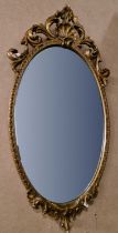 A gilt framed oval bevelled wall mirror with shell and scroll surmount 74cm x 37cm, together with