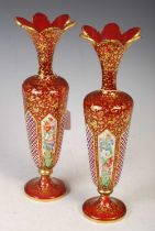 A pair of late 19th century Bohemian opaque white overlaid ruby glass vases, decorated with