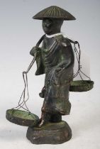 A Chinese bronzed figure of a plantation worker with carrying pole suspending two baskets, 14cm