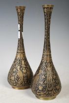 A pair of Eastern brass bottle vases, decorated with birds, flowers and scrolls on a black-