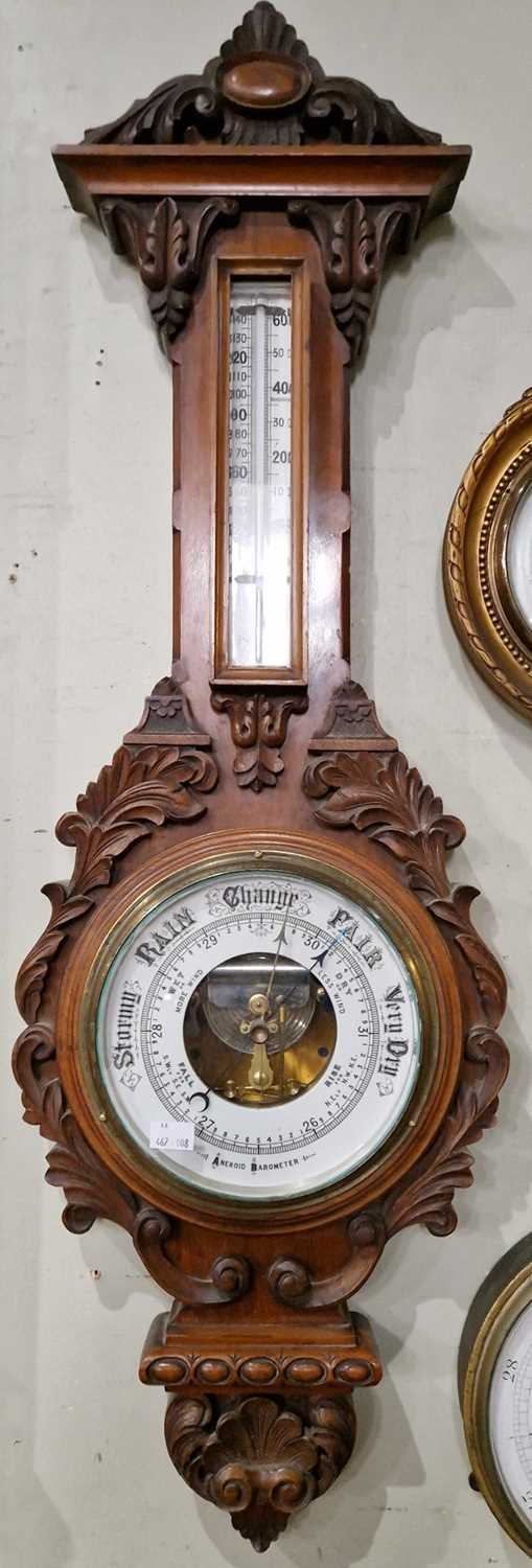 A Victorian carved mahogany aneroid barometer within elaborately carved shell and scroll surround.