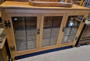 An oak Arts & Crafts side cabinet, the glazed centre panel flanked by two cupboard doors with