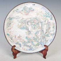 A Chinese Canton enamel circular dish, Qing Dynasty, decorated with a mountain landscape with pine