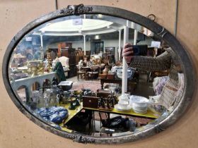 An early 20th century pewter mounted oval bevelled wall mirror, with embossed foliate and scroll