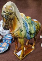 A Chinese pottery model of a horse, decorated with green, blue, brown and ochre coloured glazes,