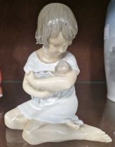 A Royal Copenhagen porcelain figure of a girl holding a doll, 13cm high.