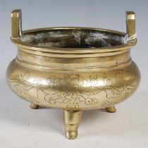 A Chinese bronze censer of circular form with two upright handles, raised on three pronged feet,