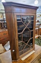 A late 19th century mahogany hanging corner cupboard with astragal glazed door.