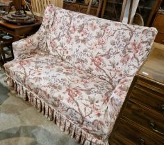 A late 19th/ early 20th century two seat sofa with floral seat cover, raised on four square