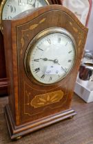 An Edwardian mahogany inlaid mantle clock with Roman numeral dial, raised on four brass bun feet