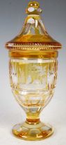 A Bohemian amber flashed clear glass goblet and cover, decorated with three wheel-cut panels,