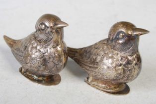 A pair of novelty white metal bird form pepper pots, the bases each with a hinged cover, one cover