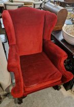 A late 19th / early 20th century wing back armchair with red velvet upholstery, the front supports