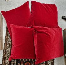 Four Oka red velvet upholstered cushions.