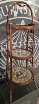 A vintage wicker woven three-tier cake stand with glazed silhouette panels, 96cm high.