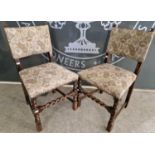 A pair of early 20th century oak dining chairs with needlework upholstery and stud details.