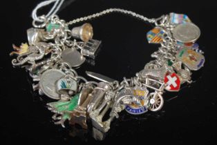 A silver charm bracelet suspending multiple Sterling silver and enamel charms, 78 grams.