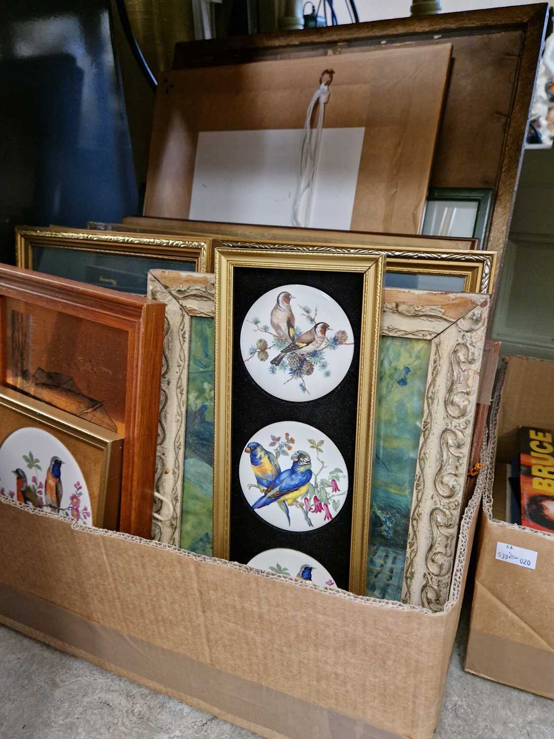 A box of assorted decorative pictures, prints and ceramic plaque with bird decoration.