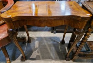 An early 20th century walnut George III style fold-over games table with green baize lining, the top