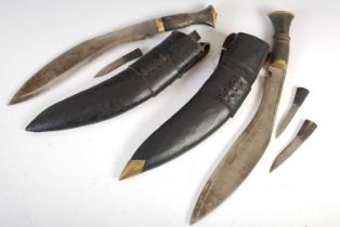 Two Kukri knives in fitted leather scabbards, one fitted with two smaller knives, the other fitted