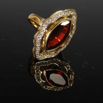 A yellow metal, garnet and diamond cocktail ring, centred with an oval faceted garnet estimated to