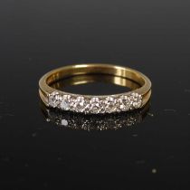 A yellow and white metal diamond set ring, set with a row of seven small round brilliant cut