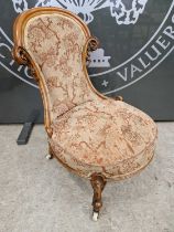 A Victorian mahogany nursing chair with floral needlework upholstery, raised on four shaped supports