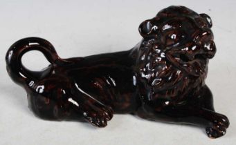 An antique glazed pottery figure of a recumbent lion, 21.cm wide x 9.5cm high.