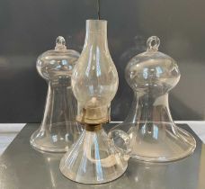 Two antique clear glass smoke bells, together with an early 20th century clear glass paraffin lamp