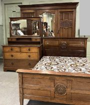 An Glasgow style Arts & Crafts oak bedroom suite comprising a three door wardrobe, the central