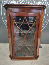 A George III mahogany, satinwood and ebonised inlaid hanging corner cupboard, the astragal glazed