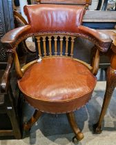 A 20th century oak and red leather captain's chair with studded detail, raised in four downswept