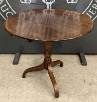 A late 19th century oak circular snap-top table with turned central column, raised on three curved