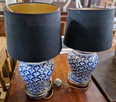 A pair of 20th century blue and white jars with covers on hardwood stands converted to table lamps