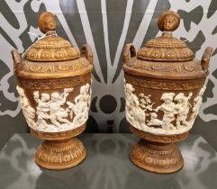 A pair of late 19th / early 20th century brown pottery twin handled urns and covers, decorated in